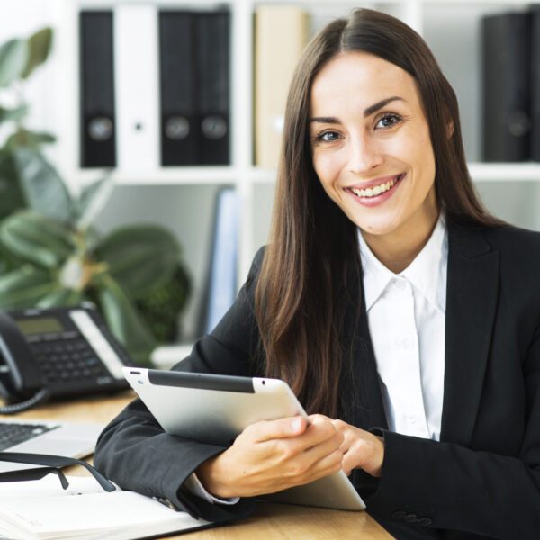 portrait-young-businesswoman-sitting-desk-holding-digital-tablet-her-hand